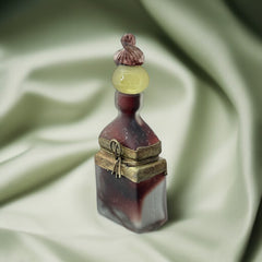 Vintage Romanian art glass perfume bottle with a plum and yellow frosted body, square base, and rounded neck, adorned with bronze wire and a sculptural stopper featuring a translucent yellow-green bead and plum-toned top.