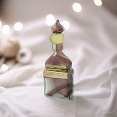 Vintage Romanian art glass perfume bottle with a plum and yellow frosted body, square base, and rounded neck, adorned with bronze wire and a sculptural stopper featuring a translucent yellow-green bead and plum-toned top.
