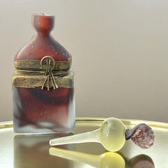 Vintage Romanian art glass perfume bottle with a plum and yellow frosted body, square base, and rounded neck, adorned with bronze wire and a sculptural stopper featuring a translucent yellow-green bead and plum-toned top.