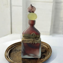 Vintage Romanian art glass perfume bottle with a plum and yellow frosted body, square base, and rounded neck, adorned with bronze wire and a sculptural stopper featuring a translucent yellow-green bead and plum-toned top.