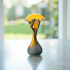 Vintage Romanian art glass vase from the 1990s featuring a frosted teal base, vibrant yellow flared top, and sculptural bronze overlay. Signed by the artist near the base. Elegant and expressive, with subtle surface variation and rich color contrast.