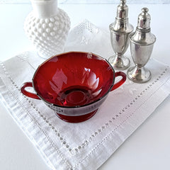 Vintage ruby red double‑handled footed glass bowls with paneled design and subtle amber rim, shown in natural light for color and detail.
