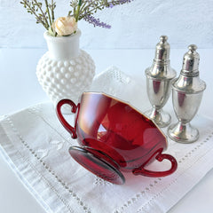 Vintage ruby red double‑handled footed glass bowls with paneled design and subtle amber rim, shown in natural light for color and detail.