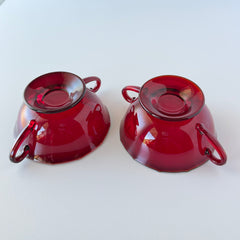 Vintage ruby red double‑handled footed glass bowls with paneled design and subtle amber rim, shown in natural light for color and detail.