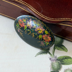 Vintage Russian hand‑painted floral black lacquer oval brooch with red, pink, and yellow flowers and gold detailing.