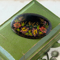 Vintage Russian hand‑painted floral black lacquer oval brooch with red, pink, and yellow flowers and gold detailing.