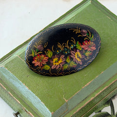 Vintage Russian hand‑painted floral black lacquer oval brooch with red, pink, and yellow flowers and gold detailing.