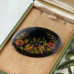 Vintage Russian hand‑painted floral black lacquer oval brooch with red, pink, and yellow flowers and gold detailing.