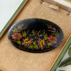 Vintage Russian hand‑painted floral black lacquer oval brooch with red, pink, and yellow flowers and gold detailing.