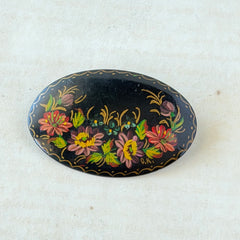 Vintage Russian hand‑painted floral black lacquer oval brooch with red, pink, and yellow flowers and gold detailing.