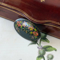 Vintage Russian hand‑painted floral black lacquer oval brooch with red, pink, and yellow flowers and gold detailing.