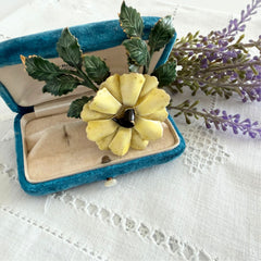 Vintage Sandor yellow enamel flower brooch with green leaves and gold tone accents.