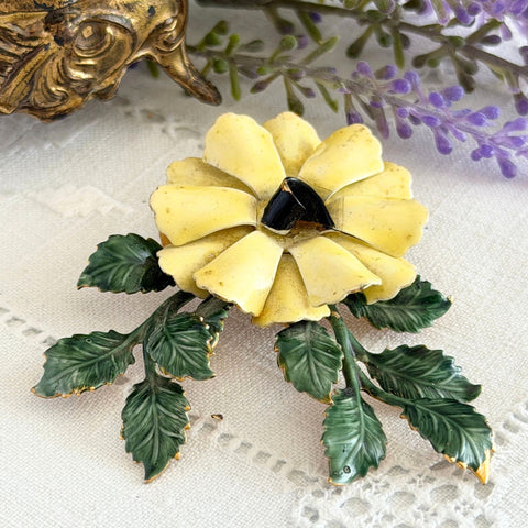 Vintage Sandor yellow enamel flower brooch with green leaves and gold tone accents.