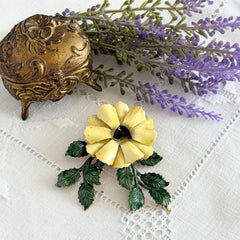 Vintage Sandor yellow enamel flower brooch with green leaves and gold tone accents.