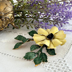 Vintage Sandor yellow enamel flower brooch with green leaves and gold tone accents.