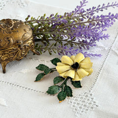 Vintage Sandor yellow enamel flower brooch with green leaves and gold tone accents.