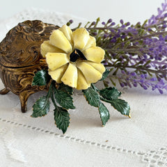 Vintage Sandor yellow enamel flower brooch with green leaves and gold tone accents.