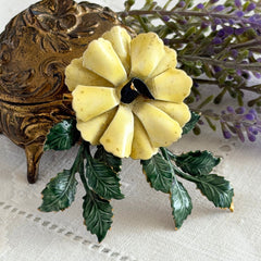 Vintage Sandor yellow enamel flower brooch with green leaves and gold tone accents.