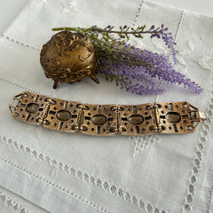 Ornate gold‑tone Sarah Coventry Granada panel bracelet with five colorful oval faux cabochons.