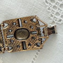 Ornate gold‑tone Sarah Coventry Granada panel bracelet with five colorful oval faux cabochons.