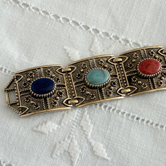 Ornate gold‑tone Sarah Coventry Granada panel bracelet with five colorful oval faux cabochons.