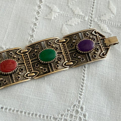 Ornate gold‑tone Sarah Coventry Granada panel bracelet with five colorful oval faux cabochons.