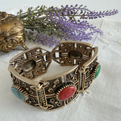 Ornate gold‑tone Sarah Coventry Granada panel bracelet with five colorful oval faux cabochons.