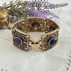 Ornate gold‑tone Sarah Coventry Granada panel bracelet with five colorful oval faux cabochons.