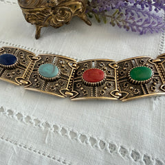 Ornate gold‑tone Sarah Coventry Granada panel bracelet with five colorful oval faux cabochons.