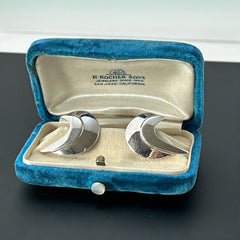 Vintage Sarah Coventry clip-on earrings with shiny silver-tone abstract crescent design; signed on back with copyright symbol, mid-century modernist style in very good condition.