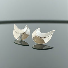 Vintage Sarah Coventry clip-on earrings with shiny silver-tone abstract crescent design; signed on back with copyright symbol, mid-century modernist style in very good condition.