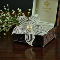 Vintage 1967 Sarah Coventry ‘Moon Flower’ brooch with silver‑tone openwork petals and a central faux pearl, shown in close detail to highlight its sculptural mid‑century design.