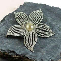 Vintage 1967 Sarah Coventry ‘Moon Flower’ brooch with silver‑tone openwork petals and a central faux pearl, shown in close detail to highlight its sculptural mid‑century design.