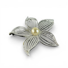 Vintage 1967 Sarah Coventry ‘Moon Flower’ brooch with silver‑tone openwork petals and a central faux pearl, shown in close detail to highlight its sculptural mid‑century design.