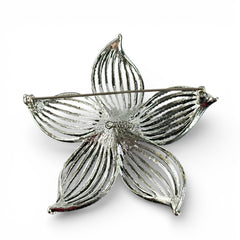 Vintage 1967 Sarah Coventry ‘Moon Flower’ brooch with silver‑tone openwork petals and a central faux pearl, shown in close detail to highlight its sculptural mid‑century design.