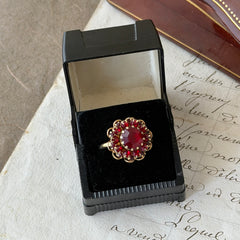 Vintage gold‑tone Sarah Coventry ring with red rhinestones in a raised floral cluster design, adjustable band, signed Sarah Cov.