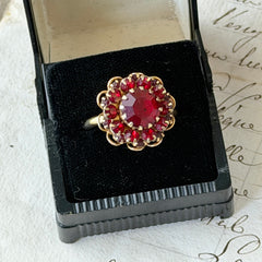 Vintage gold‑tone Sarah Coventry ring with red rhinestones in a raised floral cluster design, adjustable band, signed Sarah Cov.