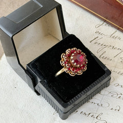 Vintage gold‑tone Sarah Coventry ring with red rhinestones in a raised floral cluster design, adjustable band, signed Sarah Cov.