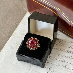 Vintage gold‑tone Sarah Coventry ring with red rhinestones in a raised floral cluster design, adjustable band, signed Sarah Cov.
