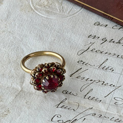 Vintage gold‑tone Sarah Coventry ring with red rhinestones in a raised floral cluster design, adjustable band, signed Sarah Cov.