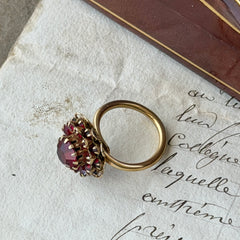 Vintage gold‑tone Sarah Coventry ring with red rhinestones in a raised floral cluster design, adjustable band, signed Sarah Cov.