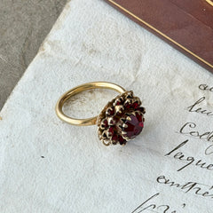 Vintage gold‑tone Sarah Coventry ring with red rhinestones in a raised floral cluster design, adjustable band, signed Sarah Cov.