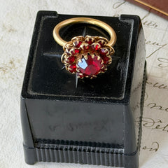 Vintage gold‑tone Sarah Coventry ring with red rhinestones in a raised floral cluster design, adjustable band, signed Sarah Cov.