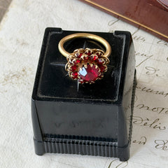 Vintage gold‑tone Sarah Coventry ring with red rhinestones in a raised floral cluster design, adjustable band, signed Sarah Cov.