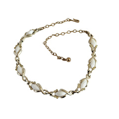 Vintage Sarah Coventry necklace with white ribbed thermoset panels, clear rhinestones, and gold‑tone links, shown from multiple angles to display its mid‑century design.
