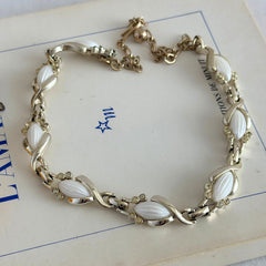 Vintage Sarah Coventry necklace with white ribbed thermoset panels, clear rhinestones, and gold‑tone links, shown from multiple angles to display its mid‑century design.