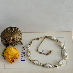 Vintage Sarah Coventry necklace with white ribbed thermoset panels, clear rhinestones, and gold‑tone links, shown from multiple angles to display its mid‑century design.