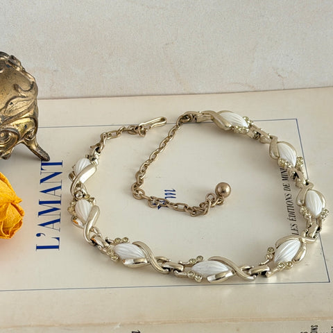 Vintage Sarah Coventry necklace with white ribbed thermoset panels, clear rhinestones, and gold‑tone links, shown from multiple angles to display its mid‑century design.