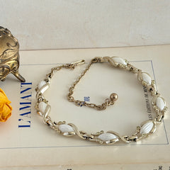 Vintage Sarah Coventry necklace with white ribbed thermoset panels, clear rhinestones, and gold‑tone links, shown from multiple angles to display its mid‑century design.
