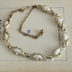 Vintage Sarah Coventry necklace with white ribbed thermoset panels, clear rhinestones, and gold‑tone links, shown from multiple angles to display its mid‑century design.